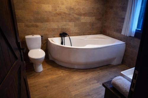 a bathroom with a white tub and a toilet at Osada Brzeziny - 25 minut od Warszawy - sauna, balia z jacuzzi, basen, altana, grill, ogród, ognisko in Brzeziny