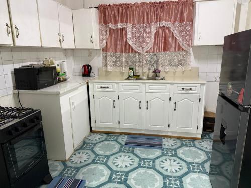 een keuken met witte kasten en een tegelvloer bij AOS Rentals in Vreed en Hoop