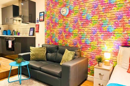 a living room with a couch in front of a brick wall at Rainbow Studio By My Getaways in Brighton & Hove