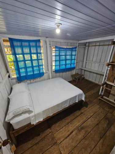 a large bed in a room with blue windows at Flor de la selva in Puerto Nariño