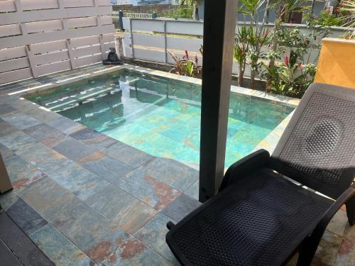 a swimming pool with a chair and a table at VILLA COLIBRI Piscine balnéo privative in Sainte-Rose