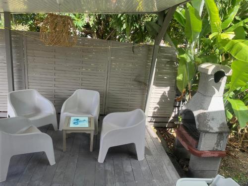 a patio with white chairs and a table at VILLA COLIBRI Piscine balnéo privative in Sainte-Rose