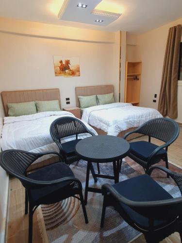 a room with two beds and tables and chairs at Andy Guest House Pyramids View in Cairo