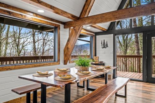 a dining room with tables and benches and large windows at High Bear Activity, Handicap Ramp, Hot Tub, Fire Table, Game Room, Family Cabin in Gatlinburg