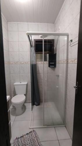 een badkamer met toilet en glazen douche bij Casa Vargem Pequena in Florianópolis