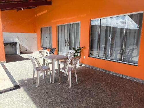 een tafel en stoelen op een patio met een oranje muur bij Casa da Hellen in Porto Seguro