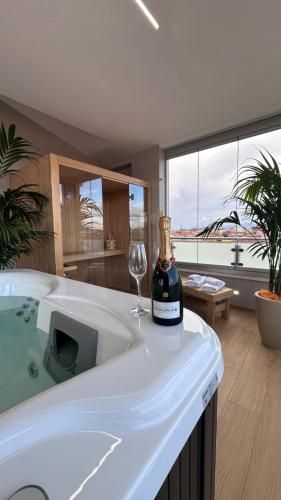 a bottle of champagne and a wine glass sitting on a bath tub at Mediterranea Apartments Aurora in Assemini