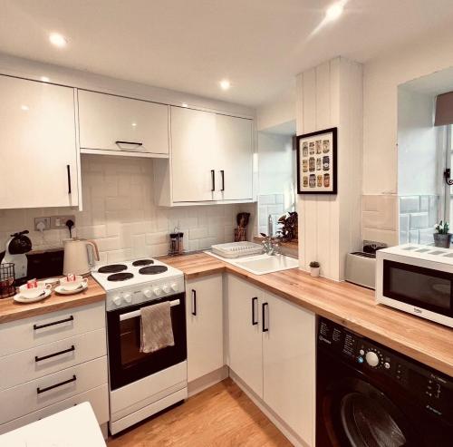 a kitchen with white cabinets and a stove top oven at Foundry Cottage, Duke St Norwich, City Centre in Norwich