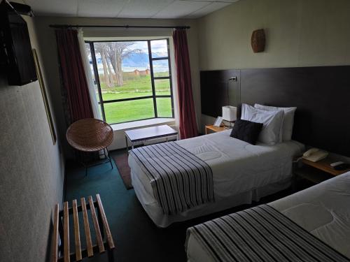 a hotel room with two beds and a window at Hotel HD Natales in Puerto Natales