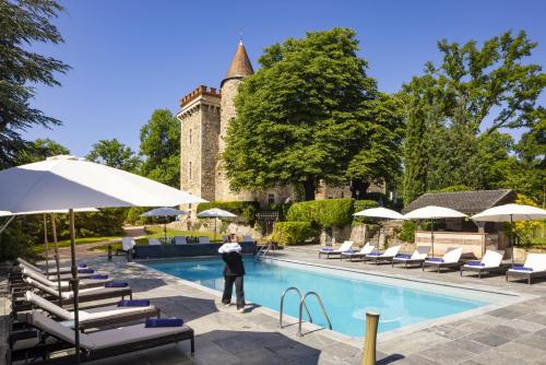 LezouxChâteau de Codignat的站在游泳池旁的男人,游泳池边摆放着椅子和遮阳伞