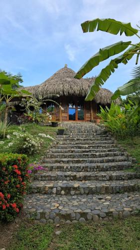 a set of stairs leading to a resort with a thatch roof at Magic Green Dentro del Parque Tayrona in El Zaino