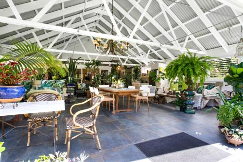 a restaurant with tables and chairs and potted plants at Noosa Valley Manor B&B in Doonan