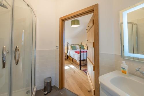 a bathroom with a shower and a sink and a bed at The-Longbarn in Ruthin