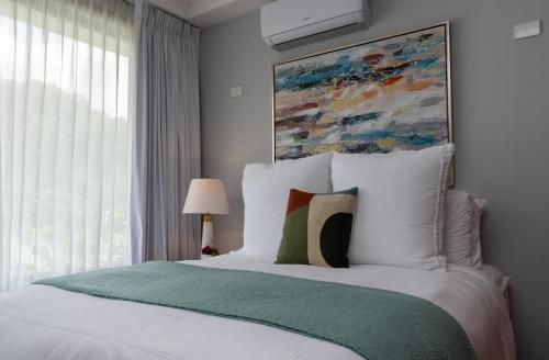 a bedroom with a bed with a painting on the wall at Corteza 2BD Gated AC Quiet Terrace Pools in Jacó