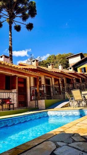 a house with a swimming pool and a palm tree at Pousada Bosque in Monte Verde