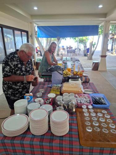 een man staat bij een tafel met borden en eten bij Lanta Summer House 1 in Koh Lanta