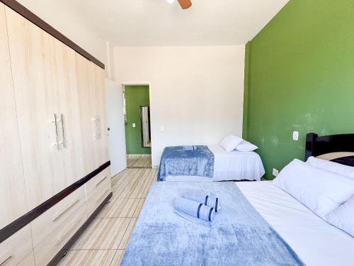 two beds in a room with green walls at Apto na beira da praia do Centro | ROMM109 in Rio das Ostras