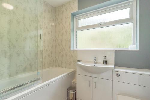 a bathroom with a sink and a tub and a window at Hendre-Llangwm in Llangwm