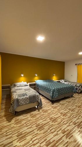 twee bedden in een grote kamer met gele muren bij Cabaña Concepcion del Valle in Salsacate