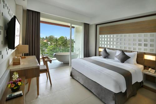 a bedroom with a bed and a bathroom with a tub at Jimbaran Bay Beach Resort and Spa by Prabhu in Jimbaran
