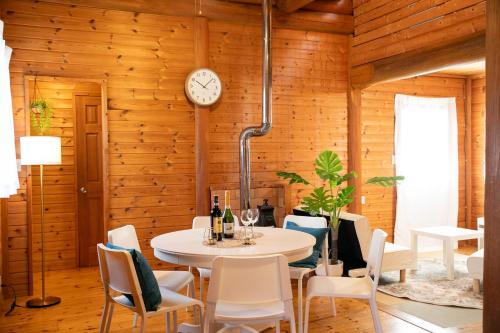 a dining room with a table and chairs and a clock at Awaji Seaside Log House in Awaji
