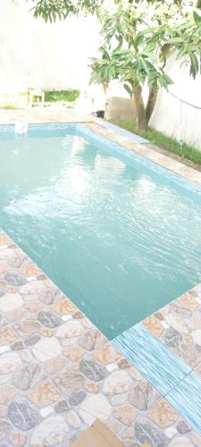 einen Pool mit blauem Wasser und Fliesenboden in der Unterkunft Maison d'hôtes Villa Mont du Pèlerin à Toamasina Madagascar in Toamasina