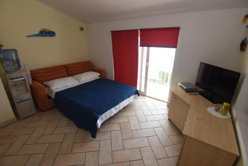 a small bedroom with a bed and a television at Apartments Roza in Miškovići