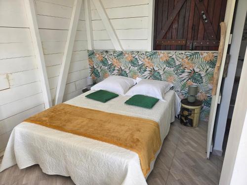 a bed with white sheets and green pillows at Guayaba in Sainte-Anne