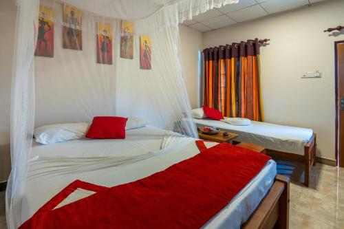 a bedroom with two beds and a red blanket at Wild Breeze in Tissamaharama