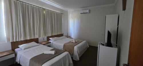 a hotel room with two beds and a flat screen tv at Hotel Norte Sul in Campo Grande