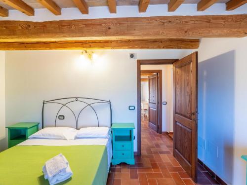 a bedroom with a green bed and a wooden ceiling at Apartment in a farmhouse with 2 swimming pools in Cagli