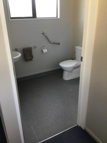 a bathroom with a toilet and a sink and a window at South Catlins Cottage in Tokanui