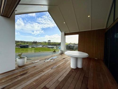 ein Badezimmer mit weißem Waschbecken und großem Fenster in der Unterkunft Light-Filled Coastal Hideaway in Raglan