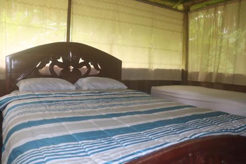 een slaapkamer met een groot bed met een houten hoofdeinde bij capybara tours and lodge in San Pedro