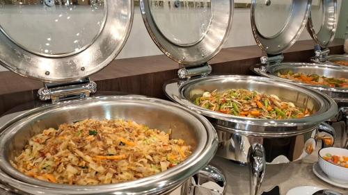 tre padelle di metallo riempite con diversi tipi di cibo di Front One Hotel Mesir Surabaya a Surabaya