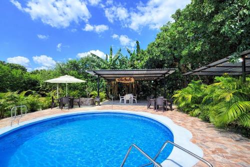 a swimming pool with a table and chairs and an umbrella at Villa Tranquila - Paraíso Privado con Piscina y Amplios Espacios Naturales con Casa Campestre in Ricaurte