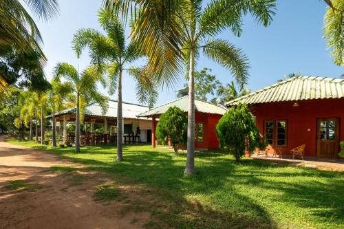 a row of palm trees in front of a red building at Wild Breeze in Tissamaharama