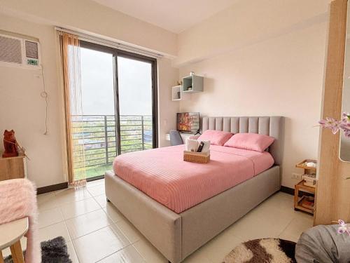 ein Schlafzimmer mit einem Bett mit rosa Kissen und einem Fenster in der Unterkunft Nuvali Sta Rosa Laguna in Pulong Cacawate
