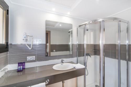 a bathroom with a sink and a shower at Hotel Baviera in Cala Ratjada