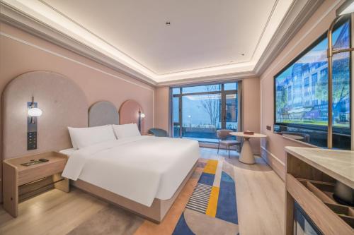 a bedroom with a large white bed and a large window at Mercure Changbai Mountain North in Antu