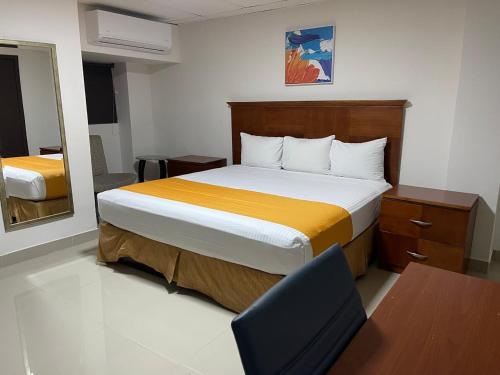a bedroom with a bed and a desk and a chair at Hotel Frontera Baja in Mexicali