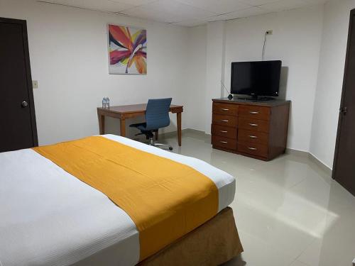 a bedroom with a bed and a desk and a television at Hotel Frontera Baja in Mexicali
