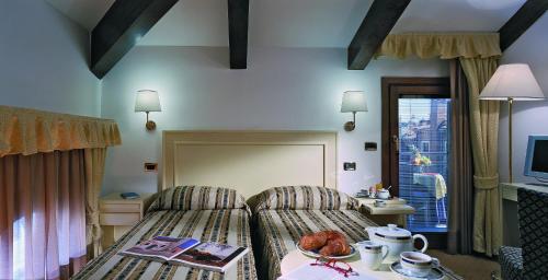 um quarto de hotel com uma cama, uma mesa e uma janela em Hotel Giudecca Venezia em Veneza