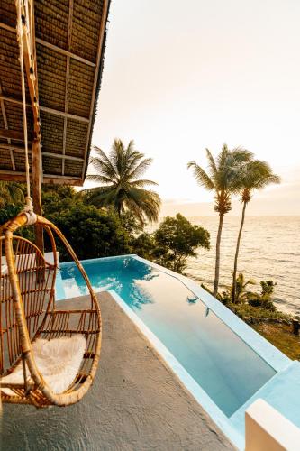 a swimming pool with a chair next to the ocean at Bintana Sa Paraiso in Mambajao