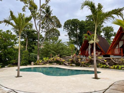 een zwembad voor een huis met palmbomen bij Dalung Tropical in Dalung