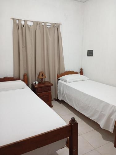 a bedroom with two beds and a window with curtains at Casa Daia con cochera y piscina in Resistencia