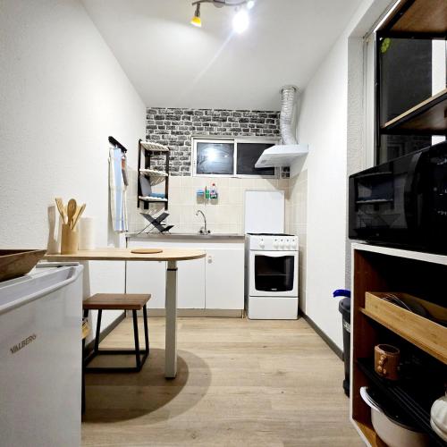 eine Küche mit einem Tisch und einer Ziegelwand in der Unterkunft Apparemment Mawen in Tarbes