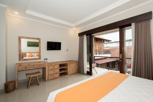 een slaapkamer met een bed en een bureau en een balkon bij Rumah Kultur in Ubud