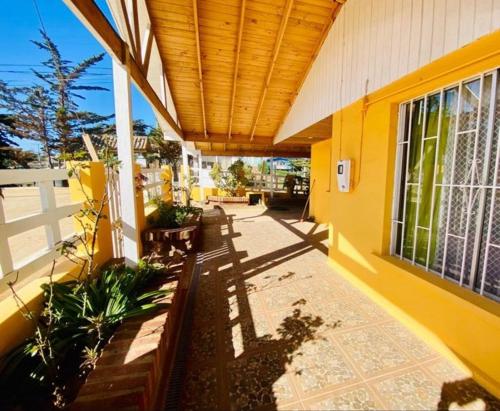a porch of a yellow building with a wooden ceiling at El tabo house in El Tabo