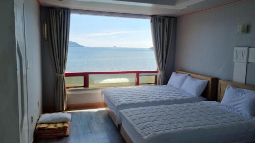 a bedroom with two beds and a large window at Namhae Beach Hotel in Namhae